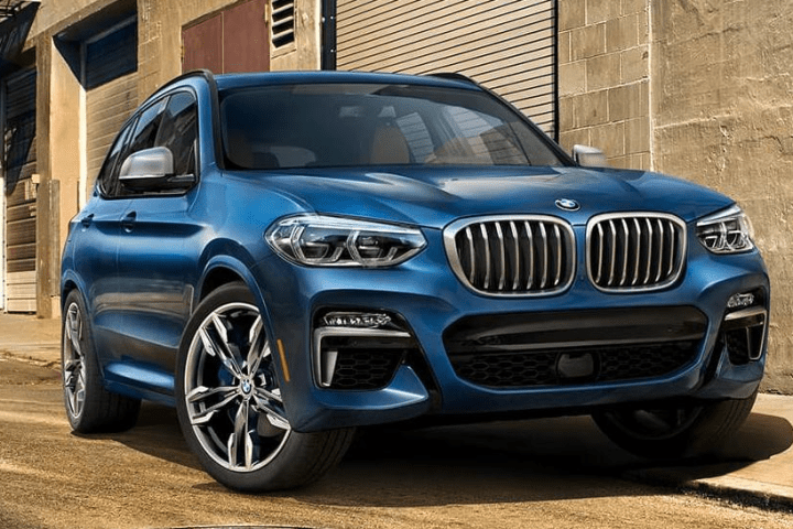 Blue SUV parked on street with industrial background.